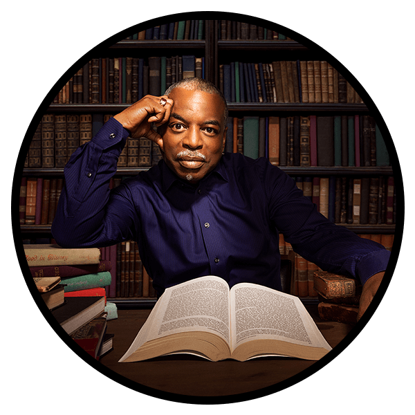 LeVar Burton sitting in a library surrounded by books